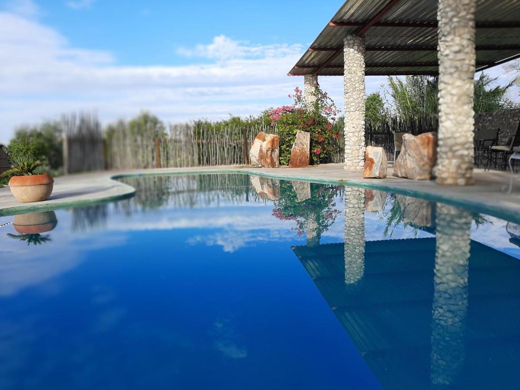 a blue swimming pool with a gazebo at Eldorado Lodge in Okaukuejo