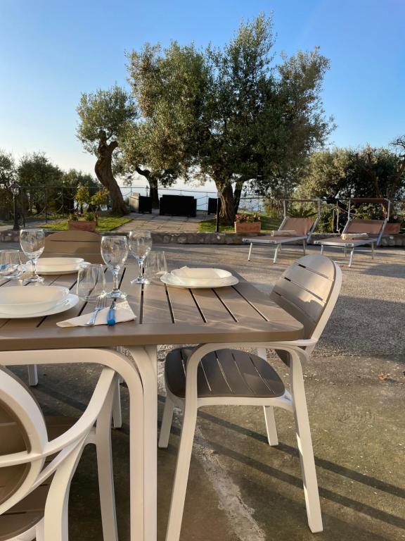 einen Holztisch mit Stühlen und Weingläsern darauf in der Unterkunft LOREN HOUSE, relaxing location with seaview in Massa Lubrense