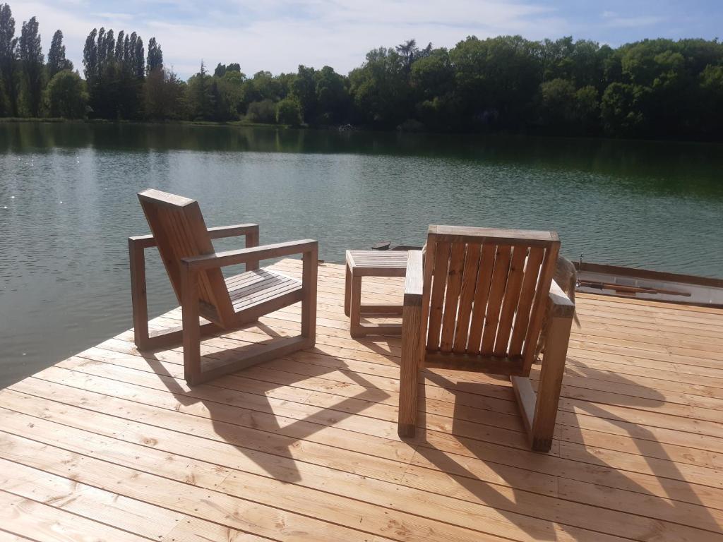 two chairs and a table on a dock near a lake at Domaine du Châtelard in Dirac