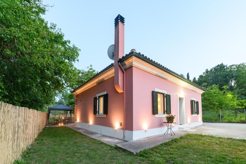 una casa rosa con una valla y un patio en Sunshine House Corfu en Anemómylos