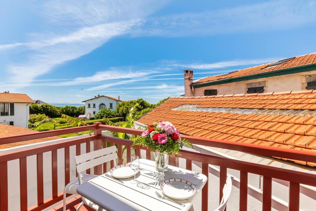 une table avec un vase de fleurs sur un balcon dans l'établissement Biarritz Beaurivage, à Biarritz