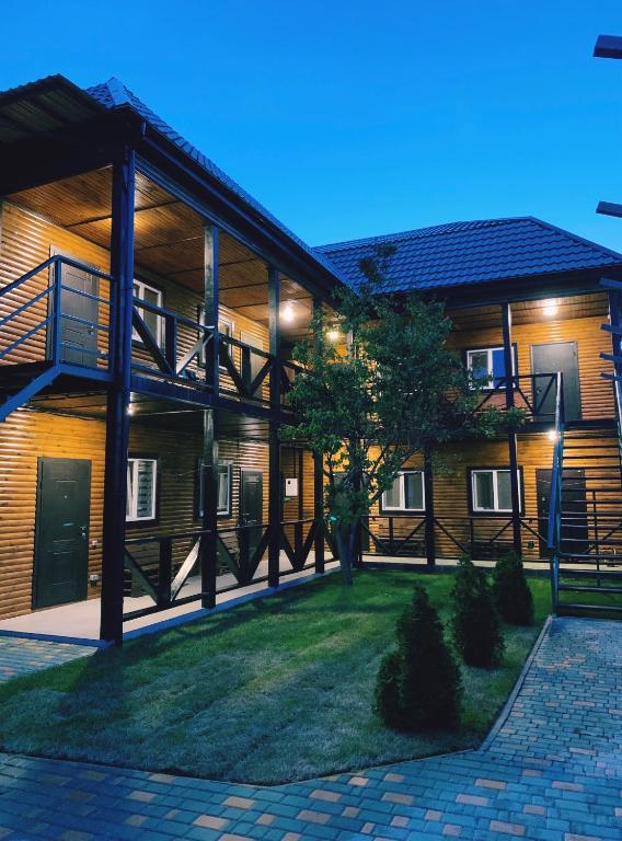 a building with a porch and a tree in front of it at Мини-отель Sunrise-Bugaz in Zatoka