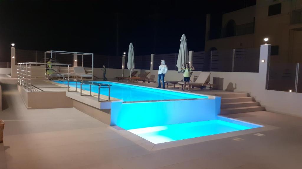 a swimming pool with people standing around it at night at Giannis Villa in Skinés