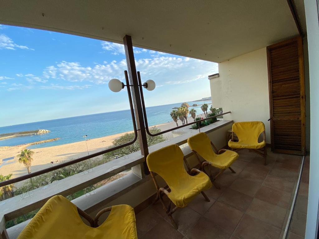 a room with yellow chairs and a view of the beach at BLANES PORT BAY VIEW in Blanes