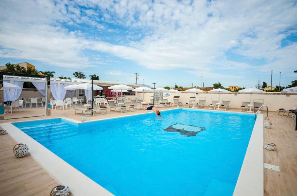 a person in a swimming pool at a hotel at Bono Vacanze Villa San Marco Luxury Holidays Homes & Hotel in Sciacca