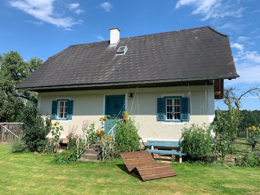 a white house with a black roof and a bench at Kellerstöckl am veganen Bio-Lebenshof "Varm - die vegane Farm" - nur für Hundefreunde und Naturliebhaber empfohlen !! in Sulb