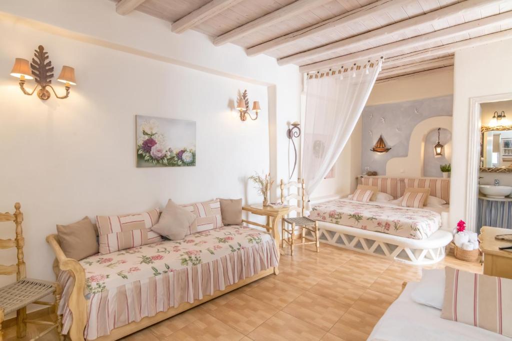 a bedroom with two beds and a table at Madalena's Family Rooms in Tinos