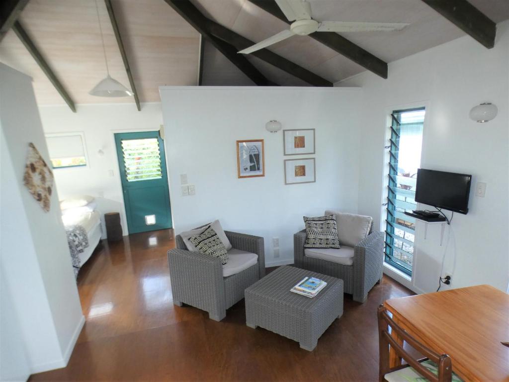 a living room with a couch and chairs and a tv at Aroa Kainga Bungalows and Apartment in Rarotonga