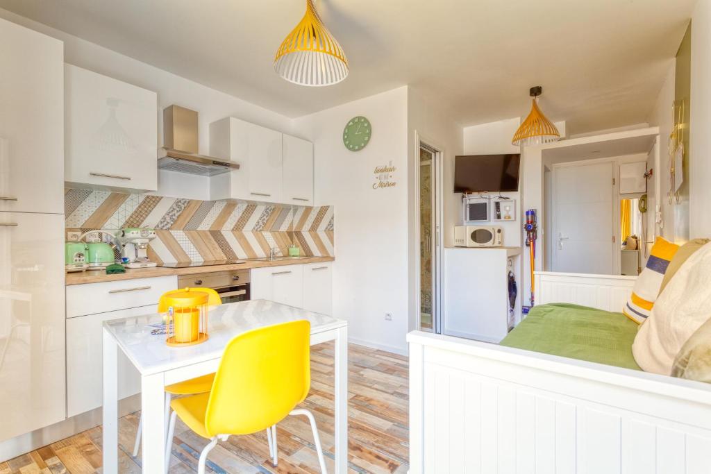 a kitchen with a table and yellow chairs in a room at T2 PRESTIGE BANDOL 2 in Bandol