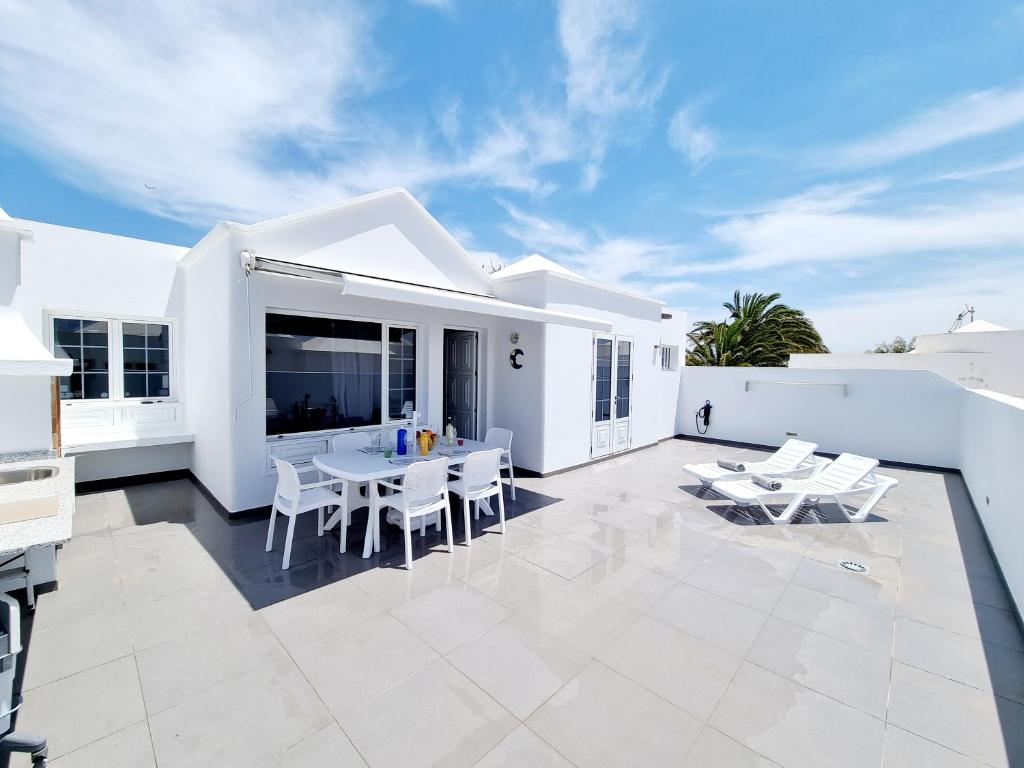een wit huis met een patio met witte stoelen en tafels bij Luxury Coral Beach first line of the sea in Playa Honda