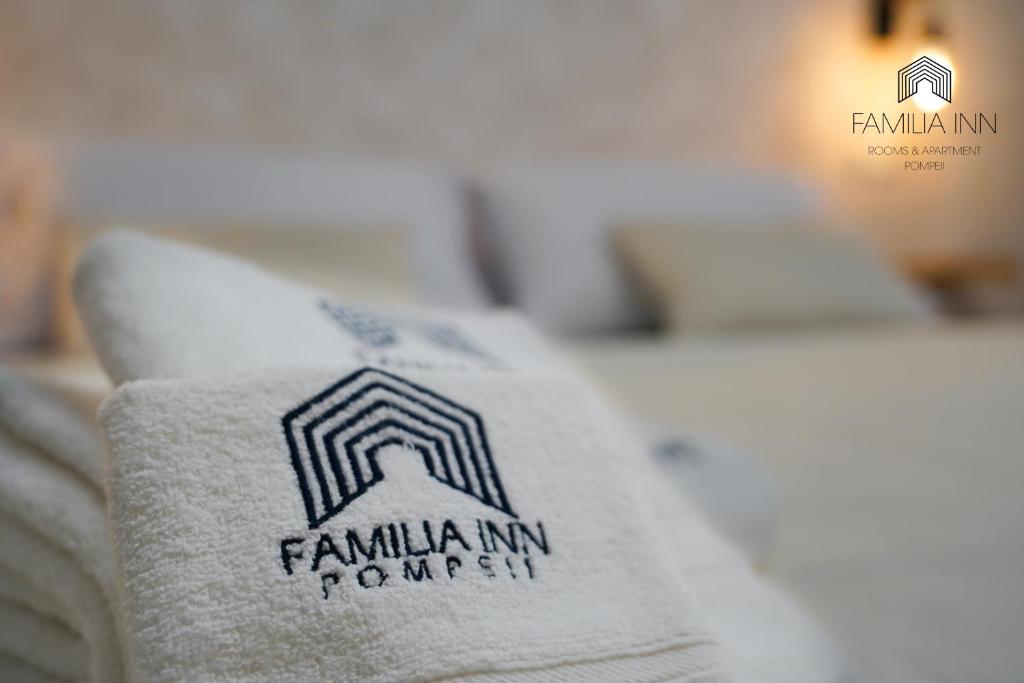 una toalla en una cama con un logotipo de empresa en ella en FamiliaINN Rooms & Apartments, en Pompeya