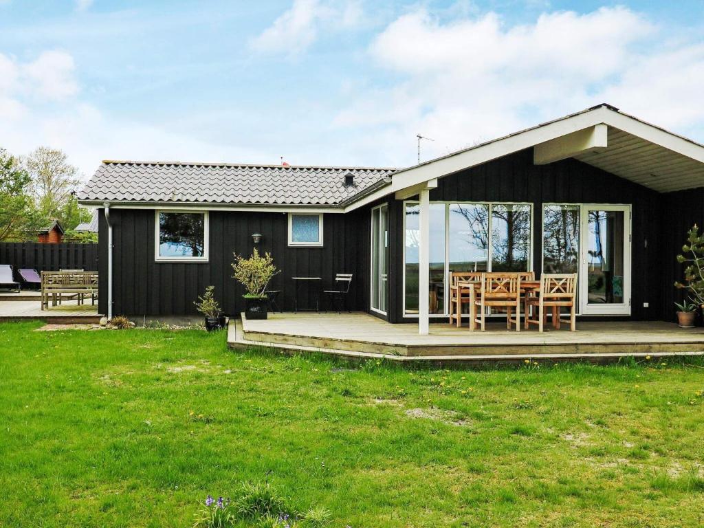 uma pequena casa preta com um alpendre e cadeiras em 9 person holiday home in Hadsund em Nørre Hurup