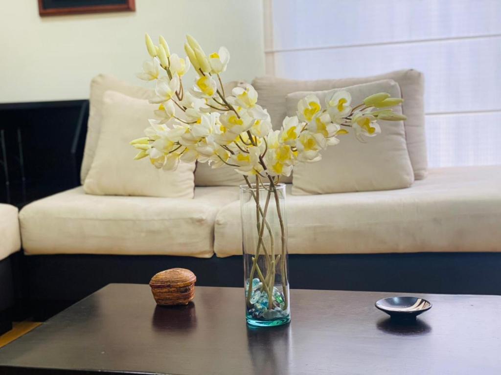 un jarrón de flores en una mesa delante de un sofá en Nice and Quiet apartment in La Carolina, en Quito