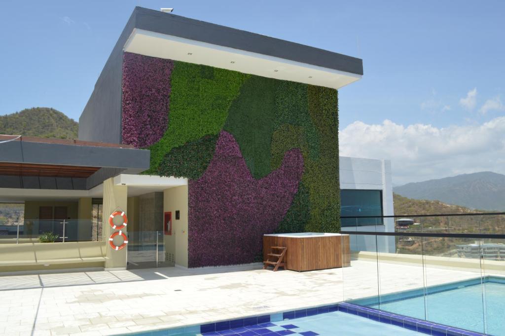 a building with a green and purple wall next to a pool at Apartasuite exclusivo VIP El Rodadero Santa Marta in Rodadero