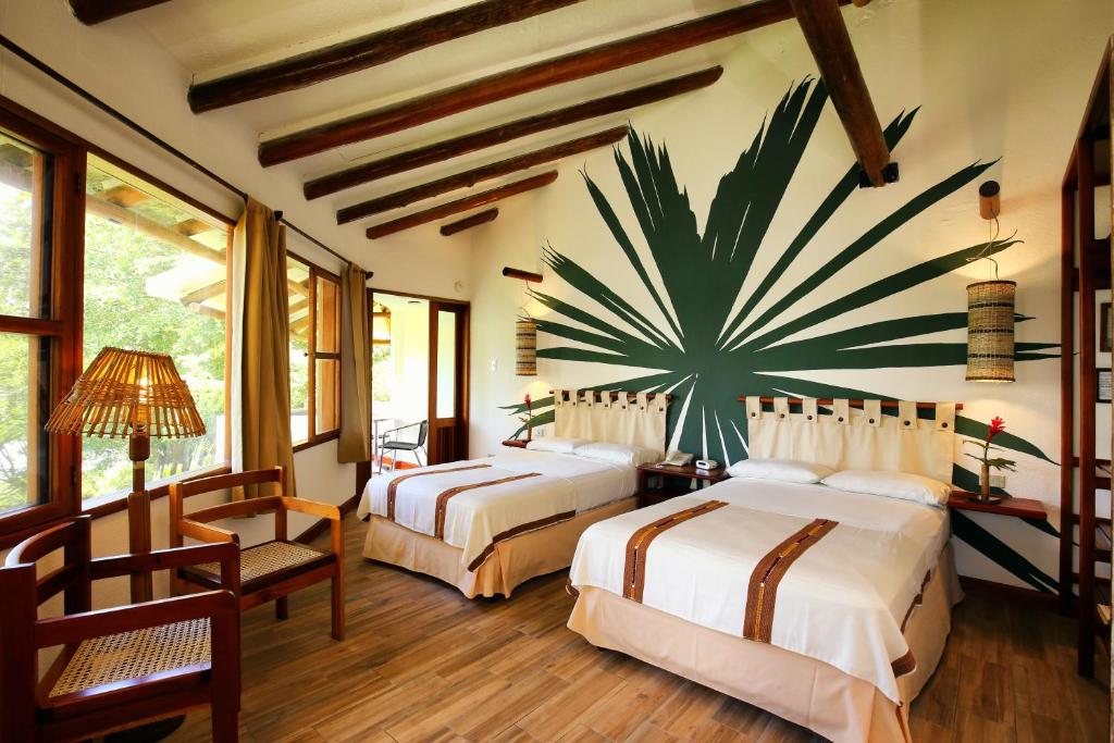 a bedroom with two beds and a large plant on the wall at Villa Maya in Flores