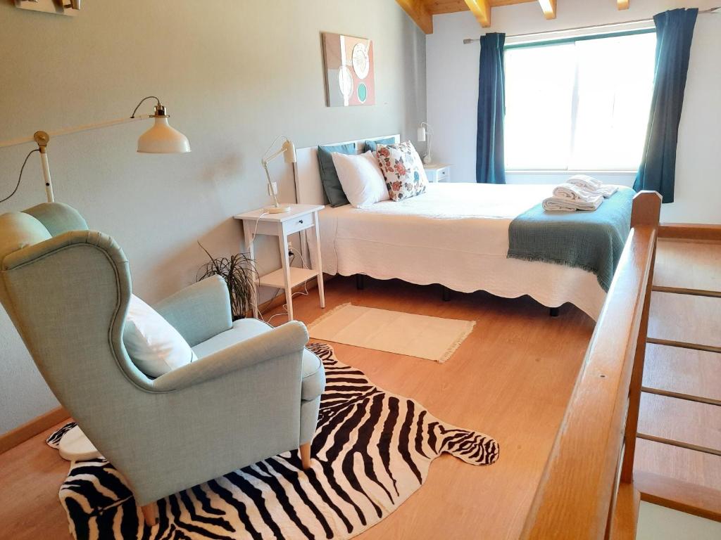 a room with a bed and a chair and a zebra rug at Apartamentos Mar I Odeceixe in Odeceixe