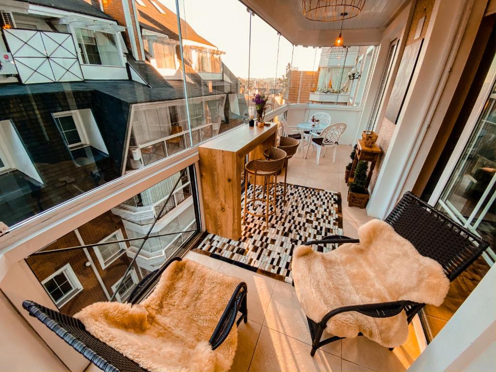 an apartment balcony with two chairs and a table at Apto Luxo 400m Rua Coberta! 3 quartos in Gramado