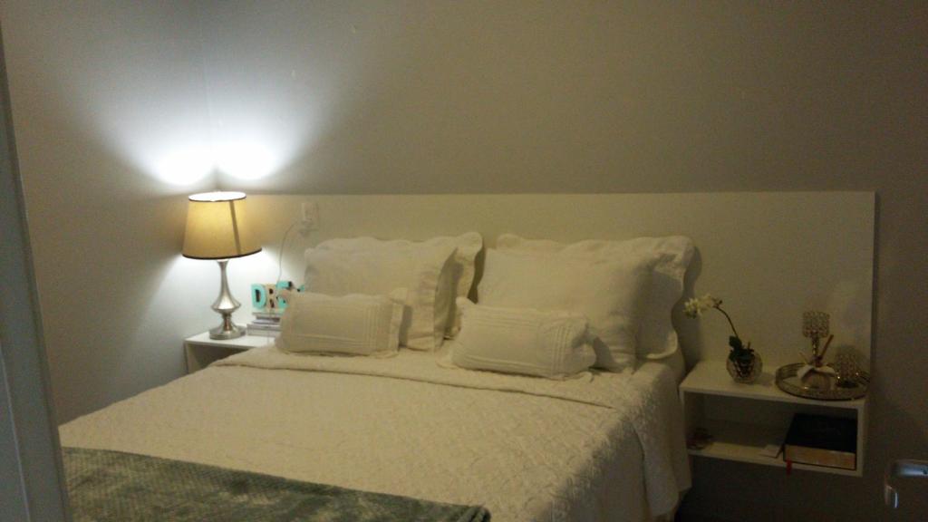 1 dormitorio con 1 cama con almohadas blancas y lámpara en Yes Vancouver Flats en Corumbá