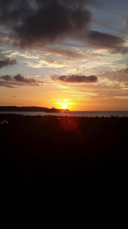 a sunset over the ocean with the sun setting at Corto Novo Maison d'hôtes-Camping in Nosy Be