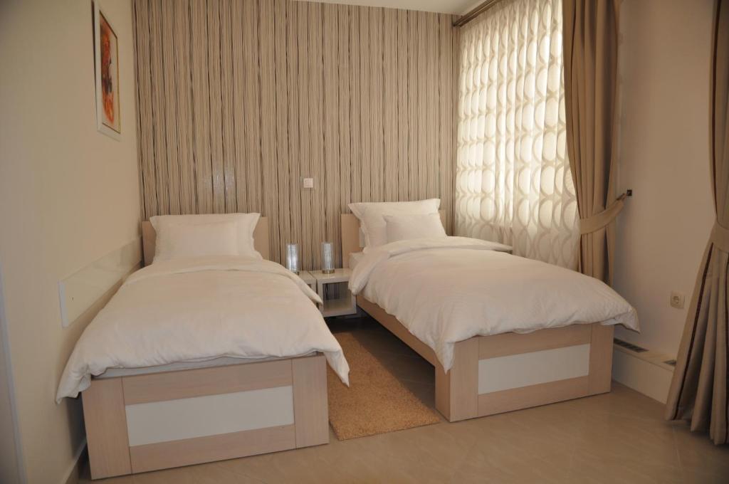 2 Betten neben einem Fenster in einem Zimmer in der Unterkunft Widder Rooms in Osijek