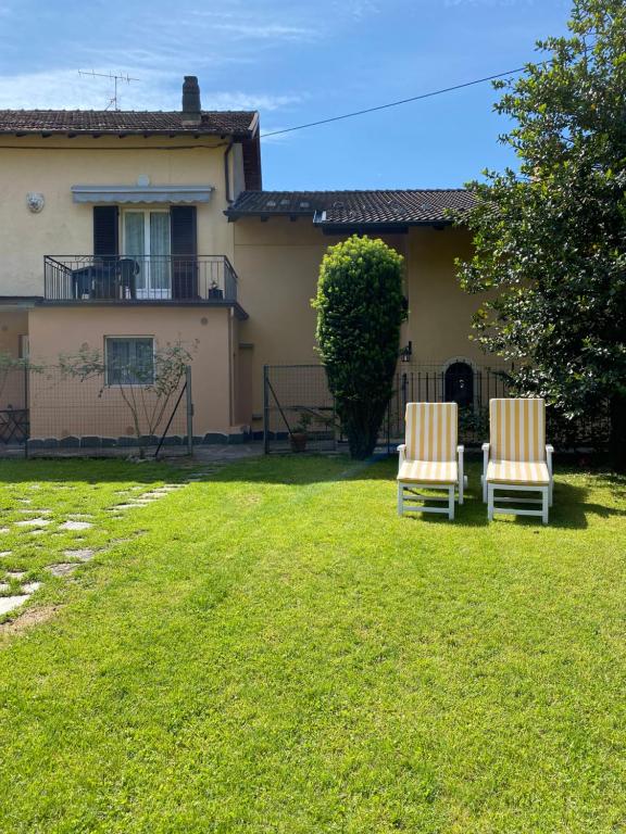 2 chaises assises dans une cour devant une maison dans l'établissement Azalea Appartamenti, à Cannobio