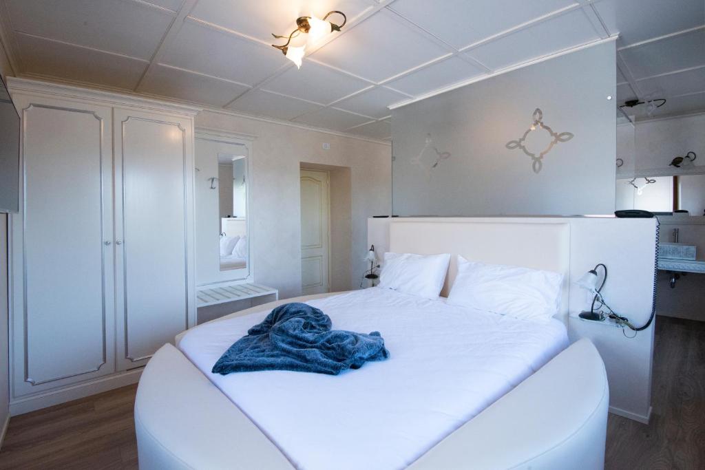 białe łóżko z niebieskim kocem w obiekcie Villa Ciardi Wellness Hotel & Ristorante w mieście Roana