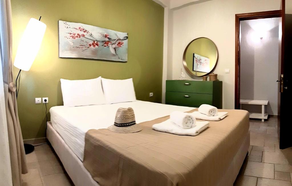 ein Schlafzimmer mit einem Bett mit Handtüchern und einem Spiegel in der Unterkunft Dioni Houses in Paralia Pantaleimonos