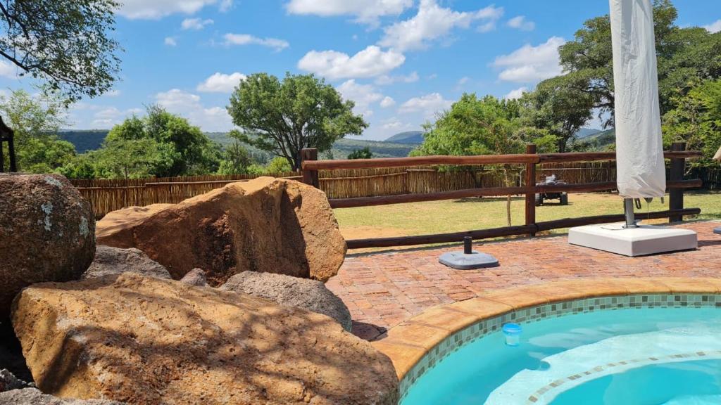 a swimming pool with rocks in a yard at Milkwood Valley Lodge, Mabalingwe in Bela-Bela