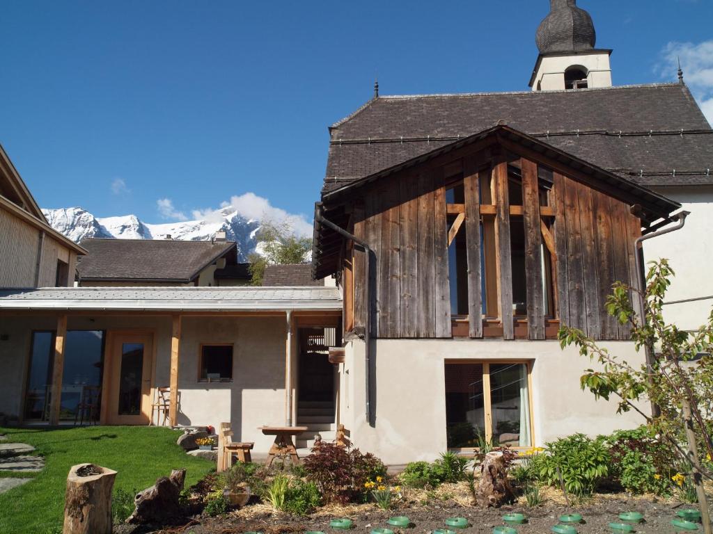 a house with a wooden roof and a church at ViVa B&B Urmein in Urmein