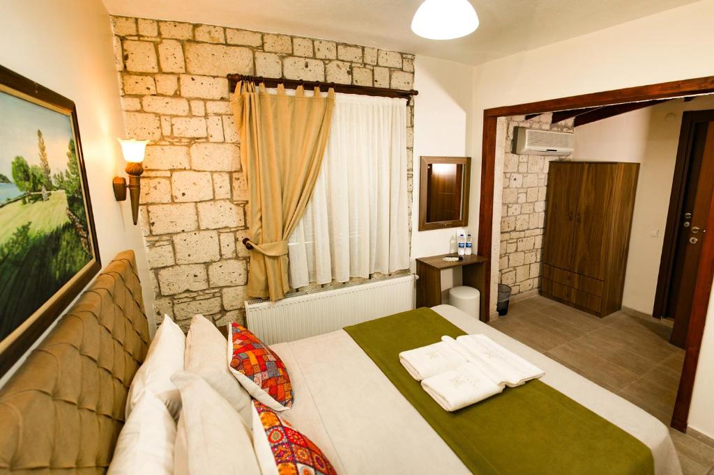 a bedroom with a bed and a stone wall at ZEVKLİLER ALAÇATI hotel in Alacati