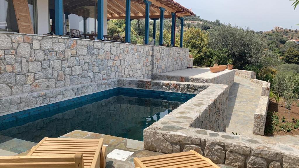 a swimming pool with two chairs and a house at Vanua house in Galatas
