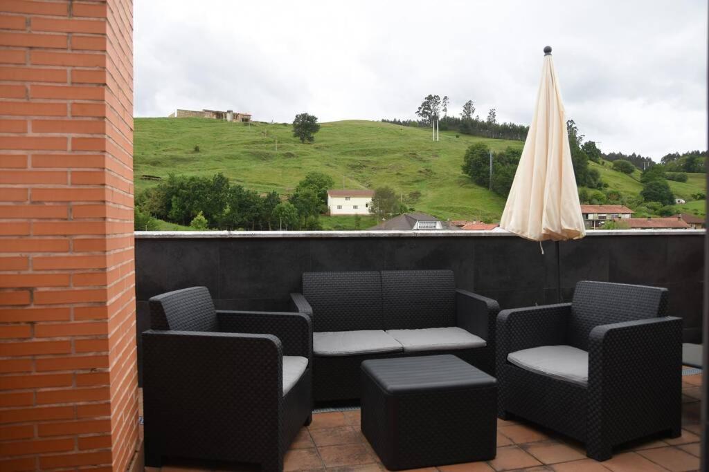 a balcony with chairs and a table and an umbrella at Dúplex con soleada terraza! in Renedo de Piélagos