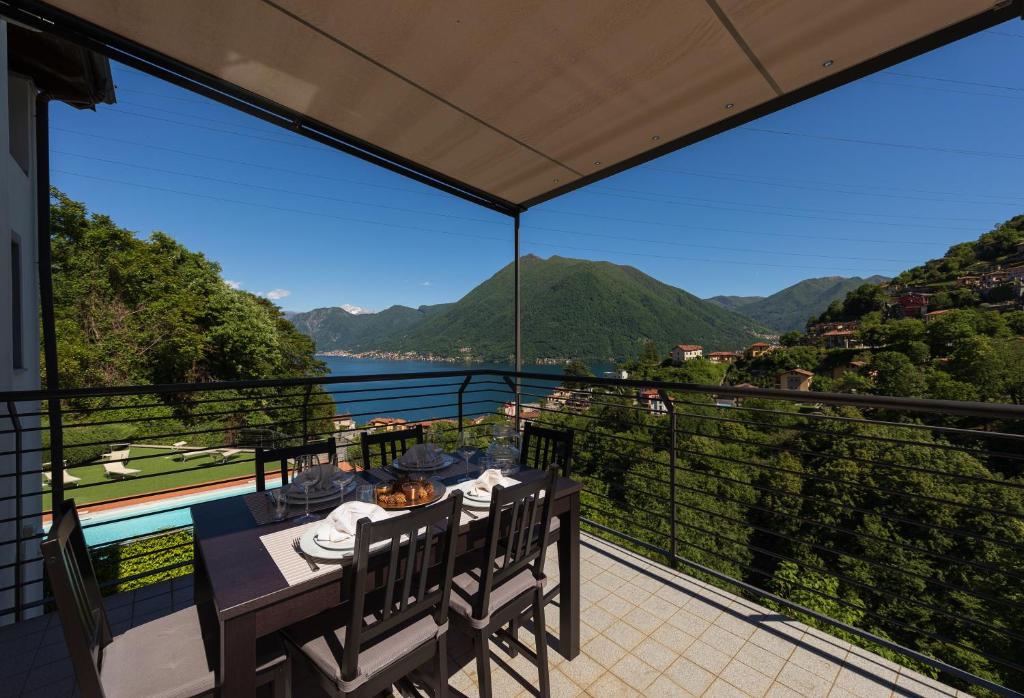 a table on a balcony with a view of the water at Maison Vespa in Argegno