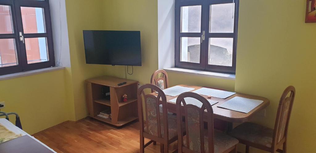 uma sala de jantar com uma mesa com cadeiras e uma televisão em Nika apartment em Piran