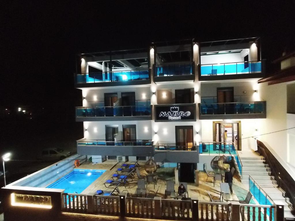 a building with a swimming pool at night at NABRO Resort in Paralia Katerinis