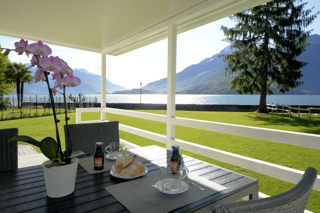 a table on a porch with a view of the water at CAMPING LA BREVA in Dongo