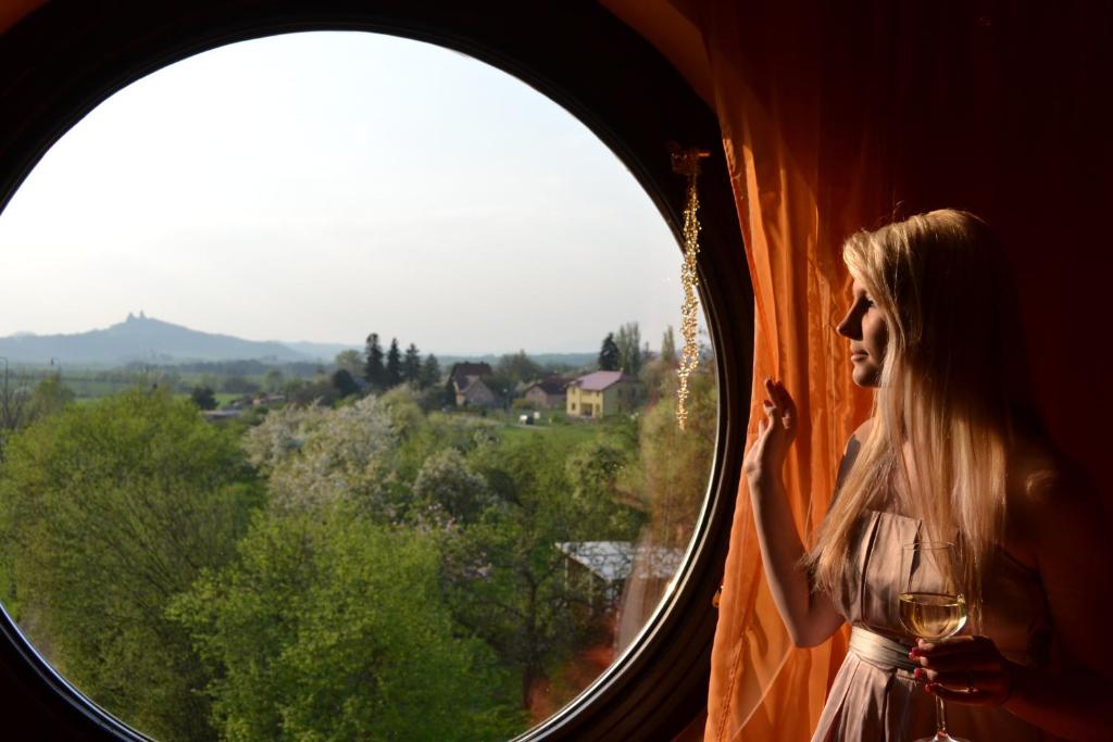 une femme debout dans une fenêtre tenant un verre de vin dans l'établissement U Zlate Brany Cesky raj, à Libuň