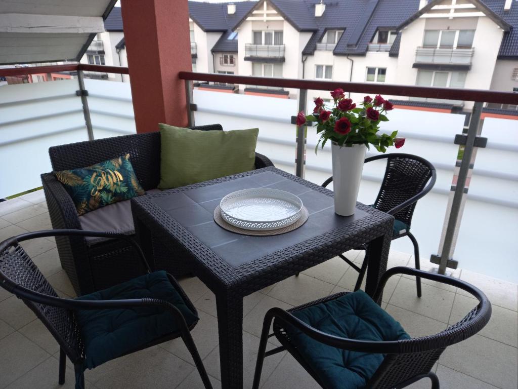 a black table with a vase of flowers on a balcony at Apartament 130 in Darłówko