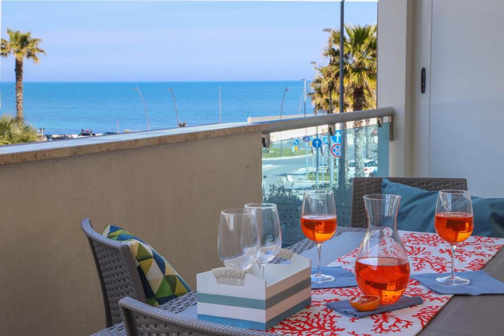 una mesa con copas de vino y vistas a la playa en A casa di Carlotta vista mare en Monopoli