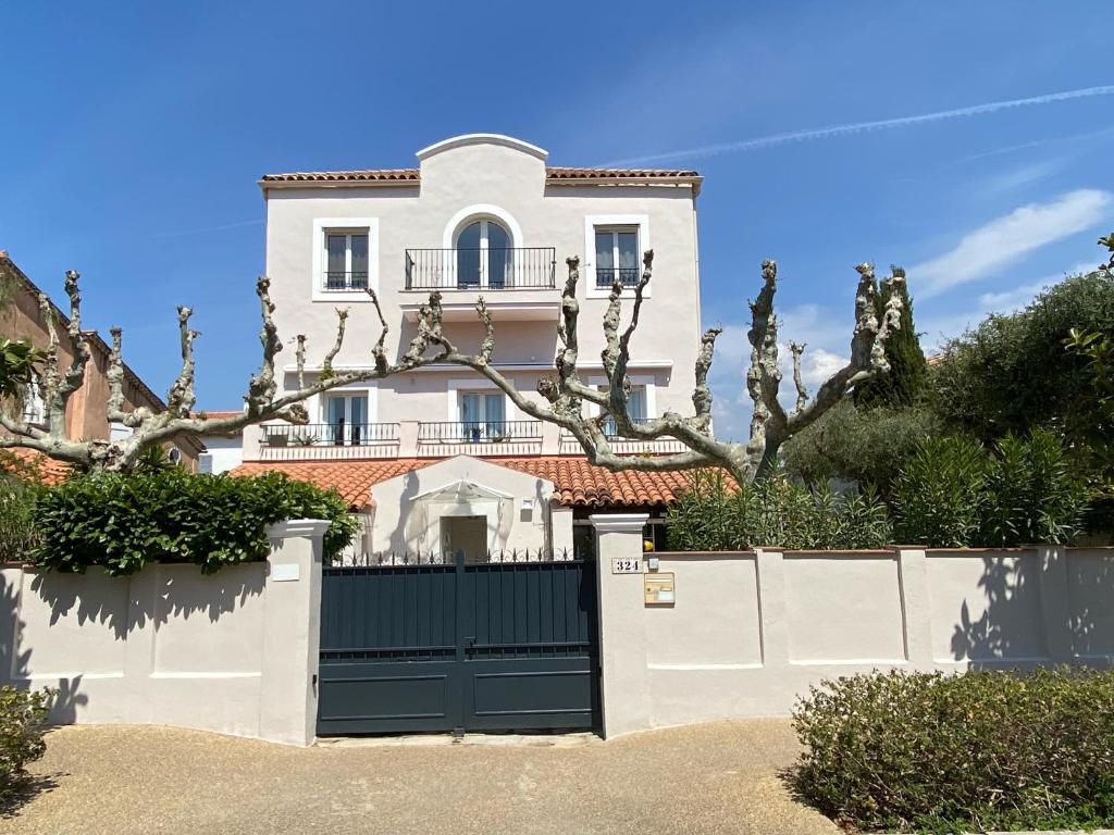 une maison blanche avec un portail et une clôture dans l'établissement Arche de Portissol Sanary Appartement de charme 4 à 6 personnes, à Sanary-sur-Mer