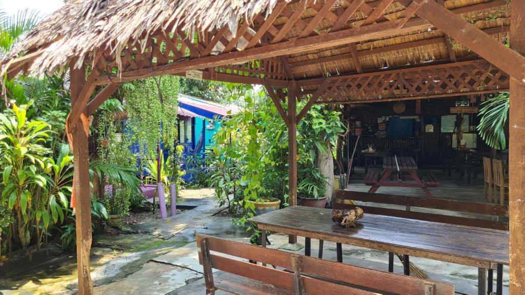 a wooden bench sitting under a wooden pergola at Gecko Guesthouse in Pantai Cenang