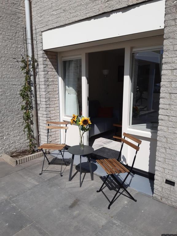 Un patio con dos sillas y una mesa con flores. en Sunny Residence, en Zandvoort