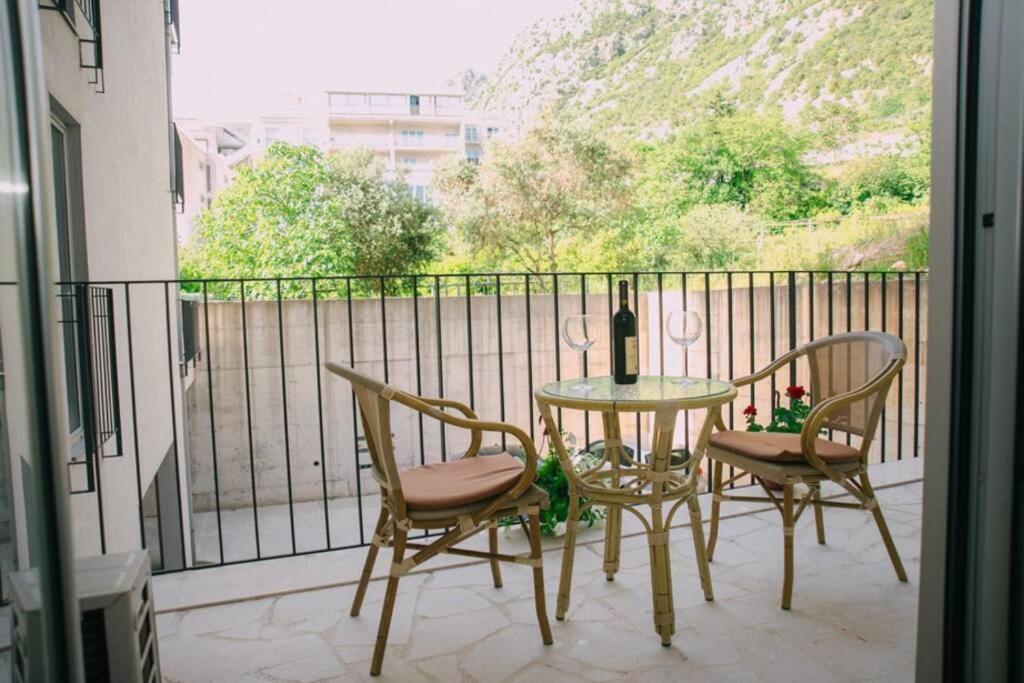 a table with two chairs and a bottle of wine on a balcony at PETRA STUDIO in Kotor