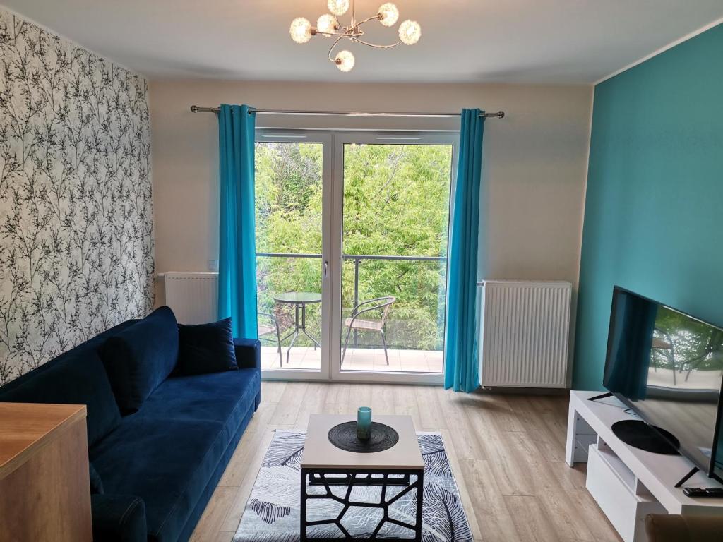 a living room with a blue couch and a window at Apartament NaGrobli in Wrocław