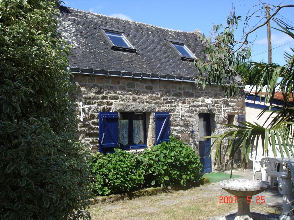 普羅梅爾的住宿－Gite La Maison du Pêcheur，一座带蓝色百叶窗和庭院的古老石头房子