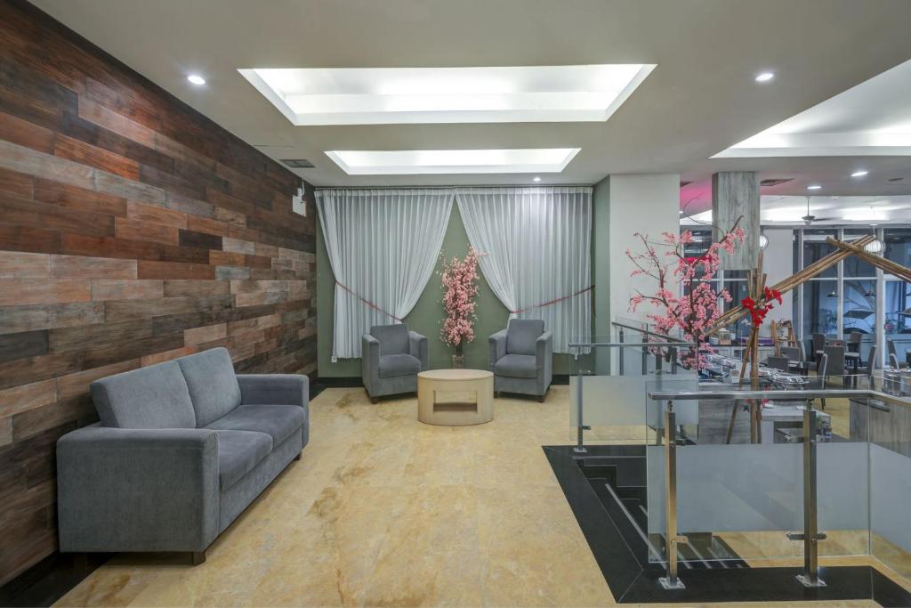 una hall con due sedie, un divano e dei fiori di Quest Hotel Darmo - Surabaya by ASTON a Surabaya