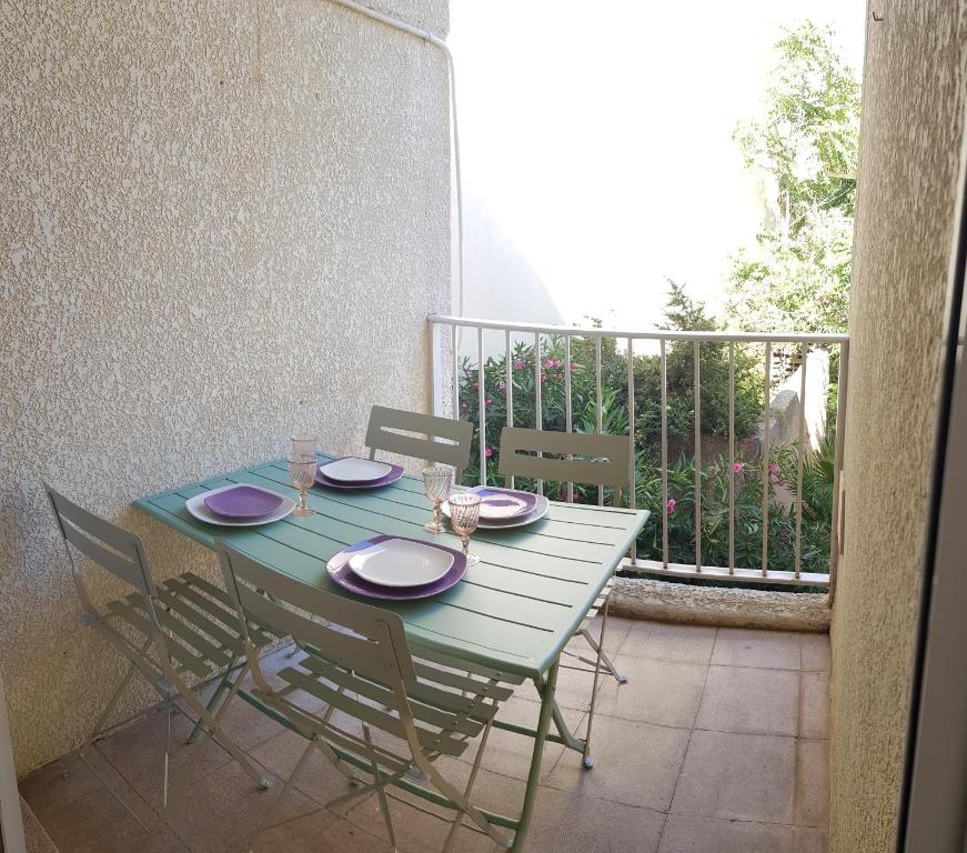 een groene tafel en stoelen op een balkon bij Duplex les pieds dans l'eau in Albitreccia