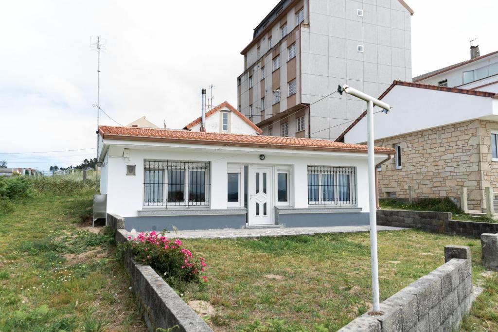 a small white house in front of a building at Casa Area da Vila in Camariñas