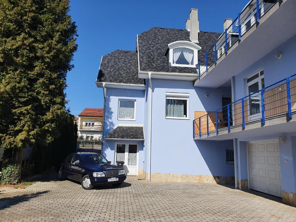 a car parked in front of a white house at Laguna Apartmanház in Hévíz