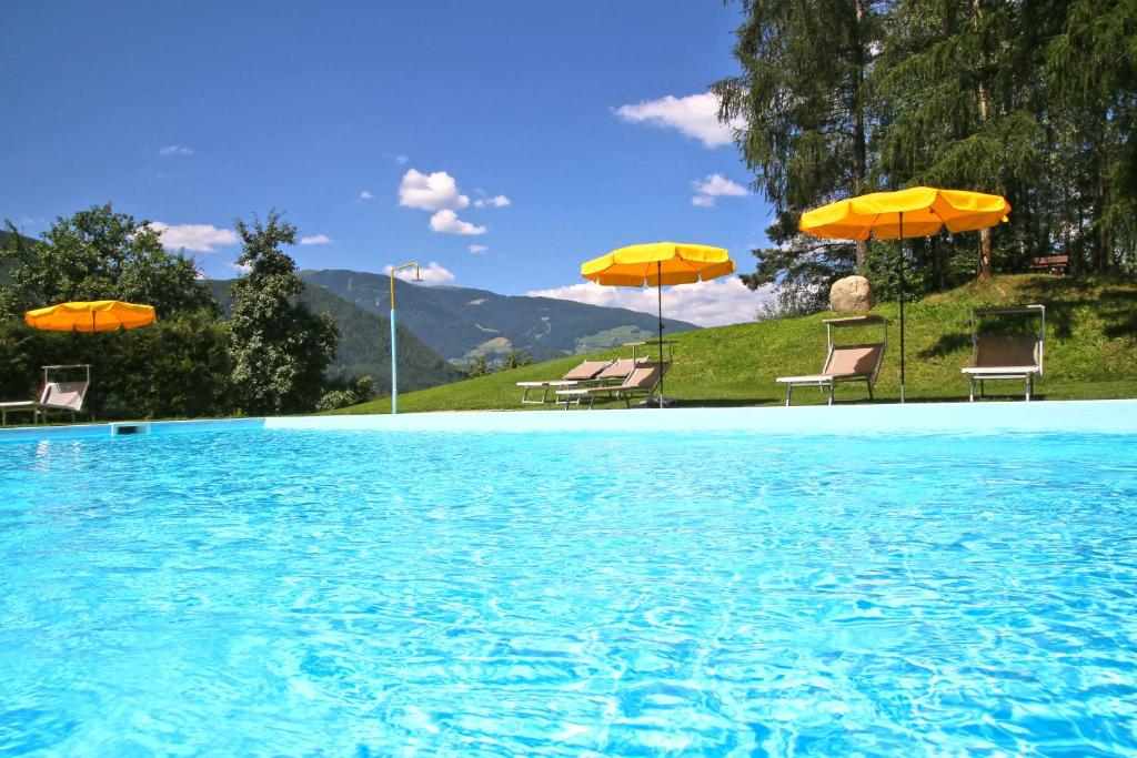 a swimming pool with chairs and umbrellas at Apartment Pichlerhof in San Lorenzo di Sebato